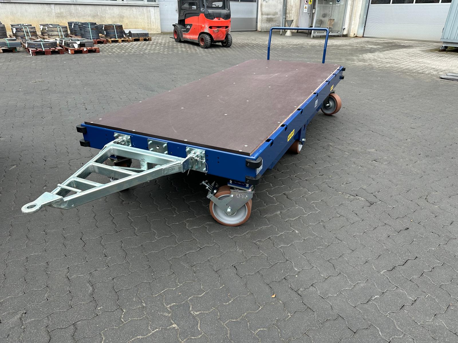 Blauer kundenspezifischer Flipper X-Move Schwerlastwagen mit Deichsel und großer Plattform auf einem Betriebshof.