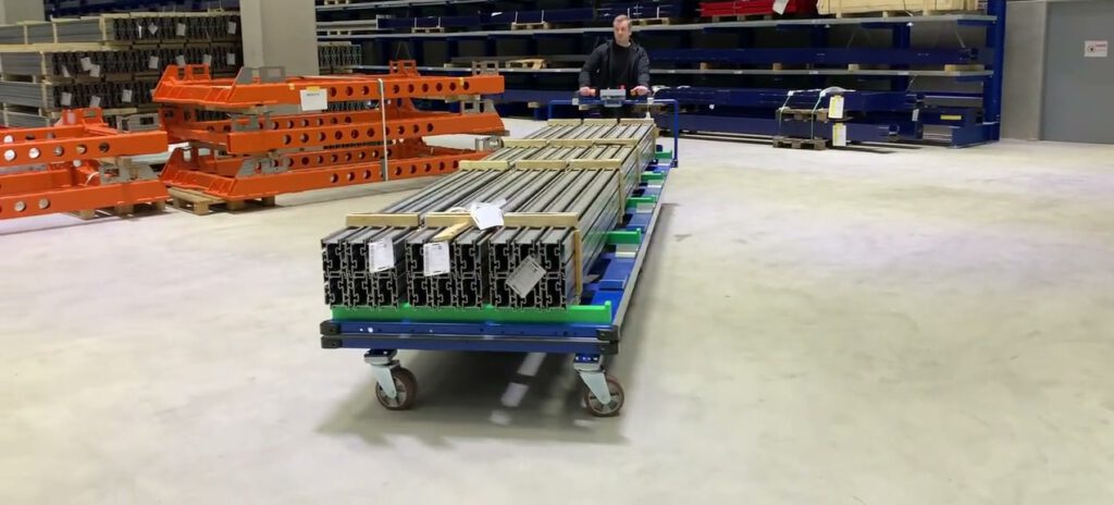 Elektrisch angetriebener Langgutwagen mit gesicherter Last in einer Industriehalle.